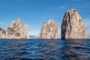Fototapeta na wymiar Sea stacks off the coast of Capri, Italy. They are named Stella, Faraglione di Mezzo with the arch, and Fraglione di Furori.