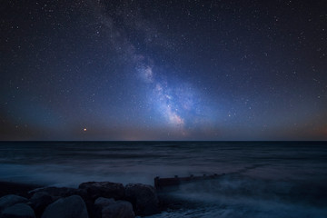Vibrant Milky Way composite image over landscape of pier at sea in Worthing England