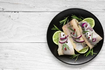 Foto op Plexiglas herring fillet with pepper, rosemary, onion and lime on black plate on white background. top view with copy space © samael334