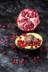 natural antioxidants, avocado fruit sprinkled with pomegranate seeds, next to a pomegranate