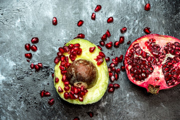 natural antioxidants, avocado fruit sprinkled with pomegranate seeds, next to a pomegranate