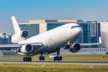 Fototapeta na wymiar White MD-11 taking off, airport buidlings in the background