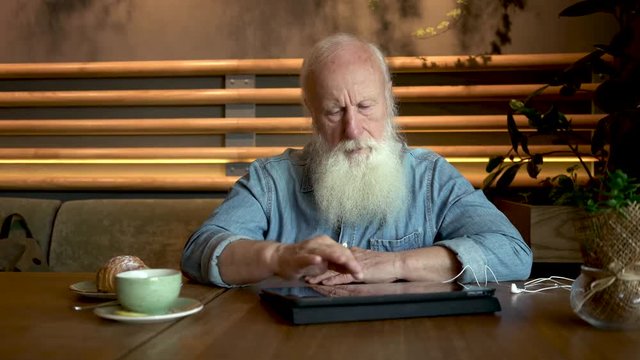 handsome old man with tablet computer in cafe. 4K