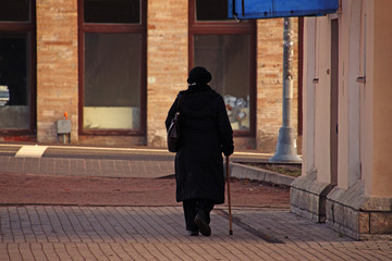elderly woman with a stick walking down the street