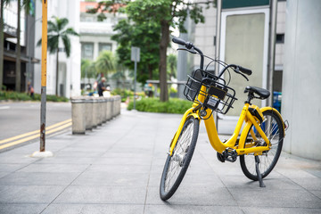 Fototapeta na wymiar Yellow bike in public park building background and view landscape of commercial building in central city