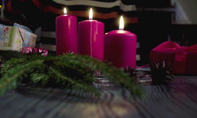 Close up Christmas gift, burning candles in a dark room. Table with Christmas decorations