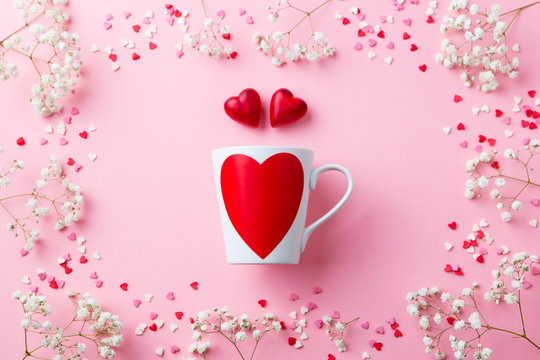 Mug with heart with sugar and chocolate hearts. Pink background. Flat lay composition. Top view.