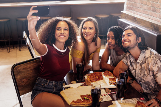 Woman taking selfie with friends at restaurant