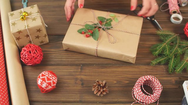 Woman s hands wrapping Christmas gift on dark wooden background.
