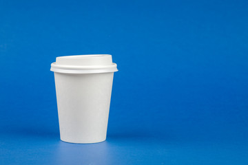 Paper coffee container with white lid on blue background. Take-away beverage container. Drink Cup template for your design