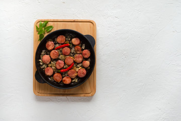 Fried sausage with onions on a portion pan. 
