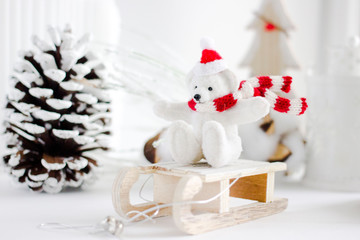 Christmas background - little white bear in a hat and scarf on a wooden sleigh