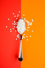 Sugar-replacing tablets spoon on orange and red background