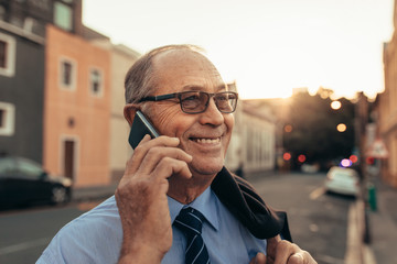 Senior businessman on city street using phone