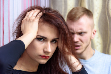 The concept of family conflict, problems, relationships of young disgruntled husband and wife in a room on the sofa.