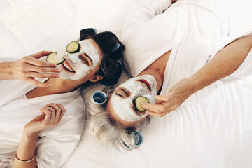 Top view of smiling mother and daughter lying on bed with face p
