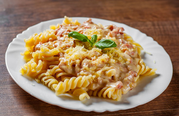 Fusilli Pasta with Carbonara Sauce and cheese in white plate on wooden table background