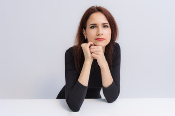 Concept of beautiful brunette girl talking on a white background at the table.