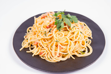 Spaghetti Carbonara with some parsley on a black plate on a white background