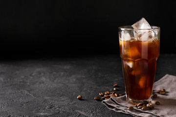tall glass cold brew coffee with ice on black or dark background - obrazy, fototapety, plakaty