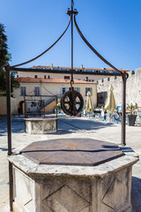 very ancient market square in the city - now a sightseeing place for tourists with a summer cafe; visible old wells with metal covers