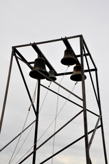 church bells on metal pylons against a cloudless sky.