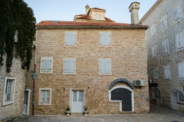 Facade of the old facing stone house with closed wooden Windows.