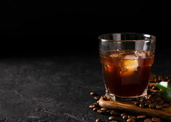 glass cold brew coffee with ice on black or dark background - obrazy, fototapety, plakaty