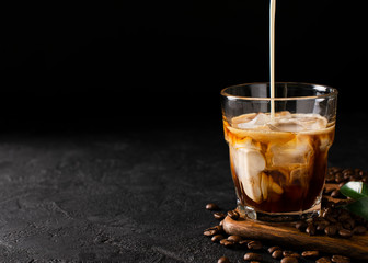 glass cold brew coffee with ice and milk on black or dark background