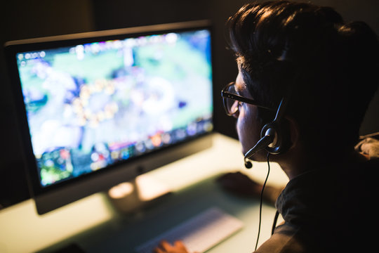 Young Indian Man With Headphones Playing Video Game In Dark Room