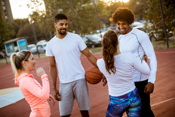 Group of multiethnic people  playing basketball on court