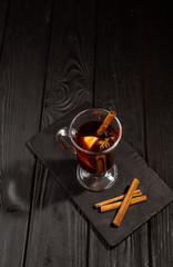 mulled wine on black wooden table, cinnamon sticks and orange, top view