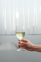 a glass of white wine in a woman's hand