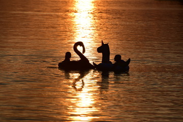 Kids Playing on an Inflatable Flamingo and an Inflatable Unicorn at Sunset