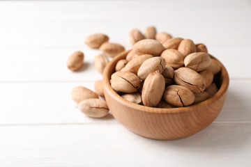 Pecan nuts in bowl on wooden table. Space for text