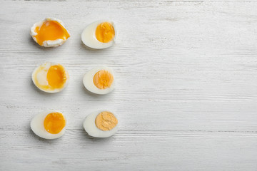 Various types of boiled eggs on white wooden background, flat lay with space for text. Cooking time