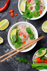 Traditional Vietnamese Soup Pho Bo with Rice Noodles, Beef and Herbs on Dark Background
