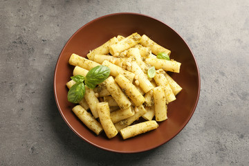 Plate of delicious basil pesto pasta on grey background, top view