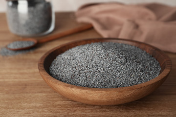 Poppy seeds in plate on wooden table