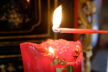 Close up incense red candle on the big red candle with fire at the chinese temple.