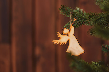 Wooden angel with a pipe on the Christmas tree on a wooden background. Rustic Christmas...