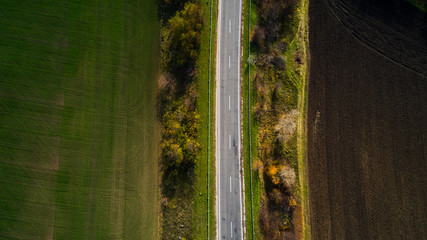 Aerial view of road in autumn. Amazing landscape with rural road near the wheat field.