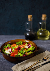 Fresh salad with tomatoes, mixed greens (arugula, mesclun, mashe) on wooden background top view.  Healthy food. Homemade food, vegetarian diet, vitamin snack (ldark version)