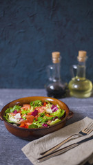 Fresh salad with tomatoes, mixed greens (arugula, mesclun, mashe) on wooden background top view.  Healthy food. Homemade food, vegetarian diet, vitamin snack (light version)