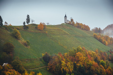 Small church at the top of the hill in autumn rainy nature. Jamnik, Slovenia.