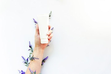 Hand cream and flowers on a pink background. Skin and hand care. Moisturizing and eliminating the dryness of the hands skin. Copy space