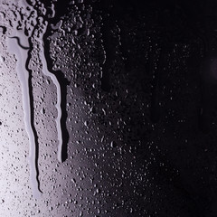 water drops on a black background with the reflection of light spots. flowing drop