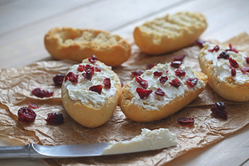 Bruschetta with cottage cheese and dried cranberries over light wooden background