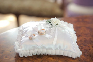 wedding rings on satin cushion with decor