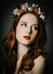 Beautiful redhead woman with wreath on gray background